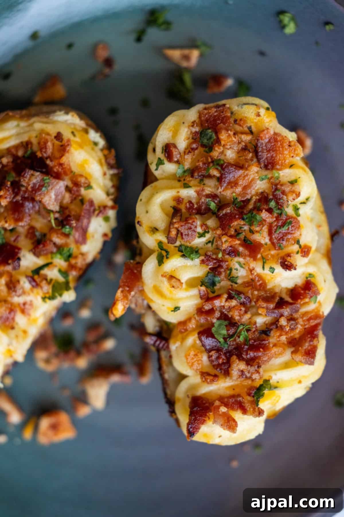 The Ultimate Double-Baked Potato 3 Close-up of a perfectly piped twice-baked potato topped with crumbled bacon and fresh green herbs, highlighting the creamy texture and crispy bits.