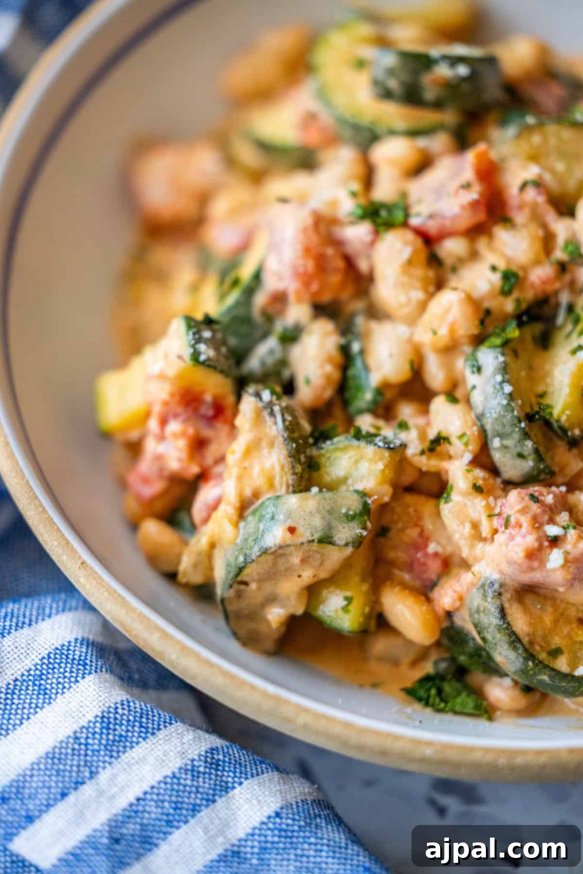 Marry Me Zucchini and Bean Delight 5 A close-up of a bowl filled with creamy Marry Me Zucchini and bean dish, showcasing vibrant zucchini slices, diced tomatoes, and tender white beans.
