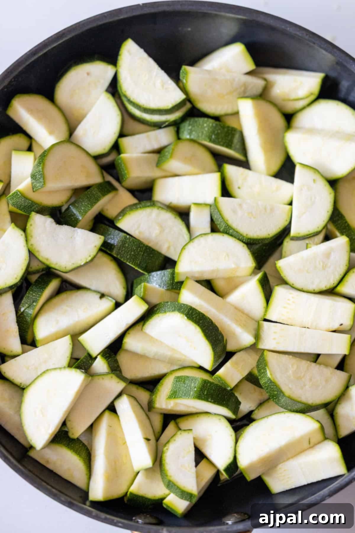 Marry Me Zucchini and Bean Delight 6 Sliced zucchini pieces in a black pan, ready to be cooked for your next marry me recipe.