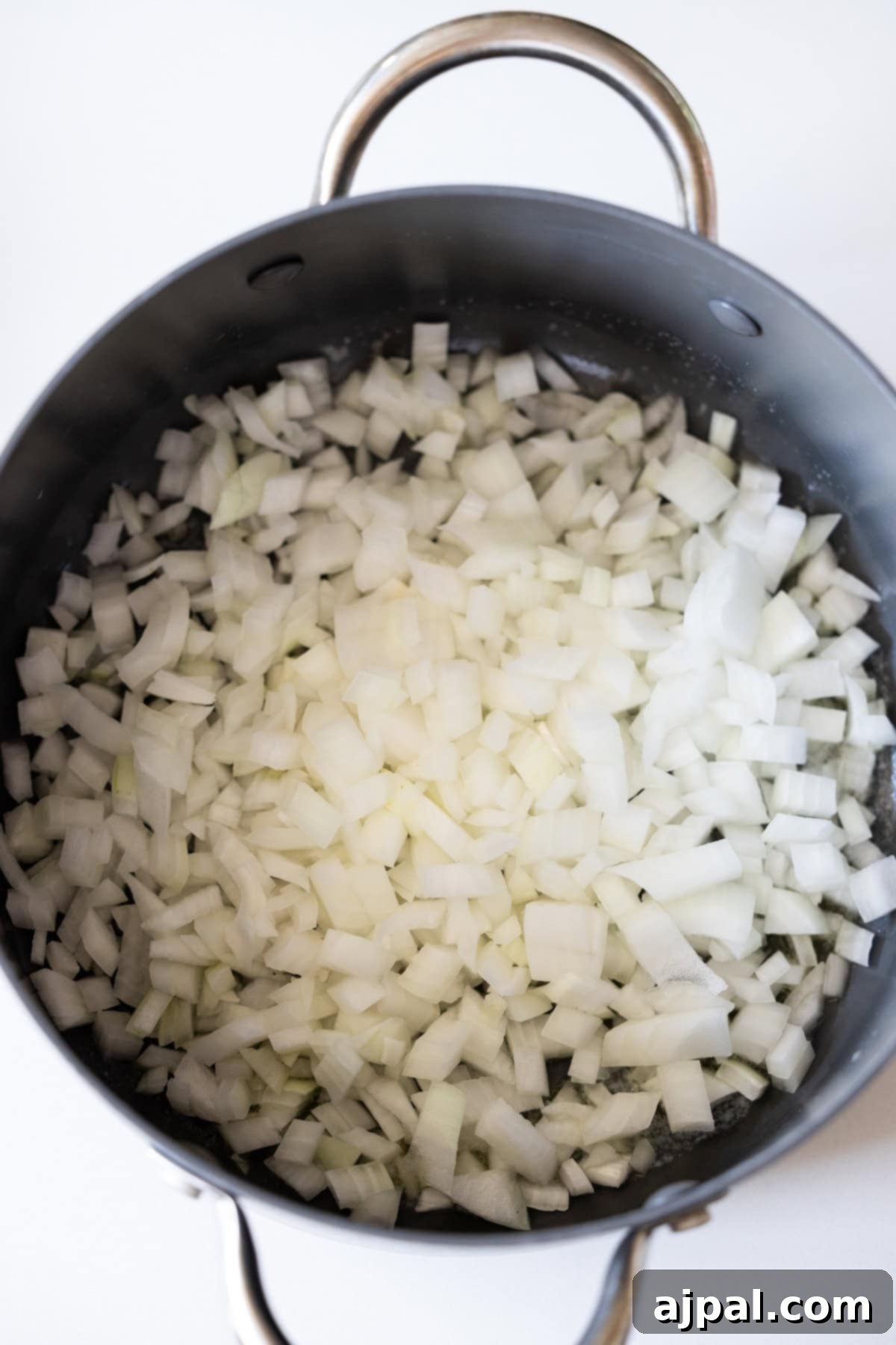 Marry Me Zucchini and Bean Delight 7 Chopped onions and zucchini in a large black pot with metal handles, ready for cooking.