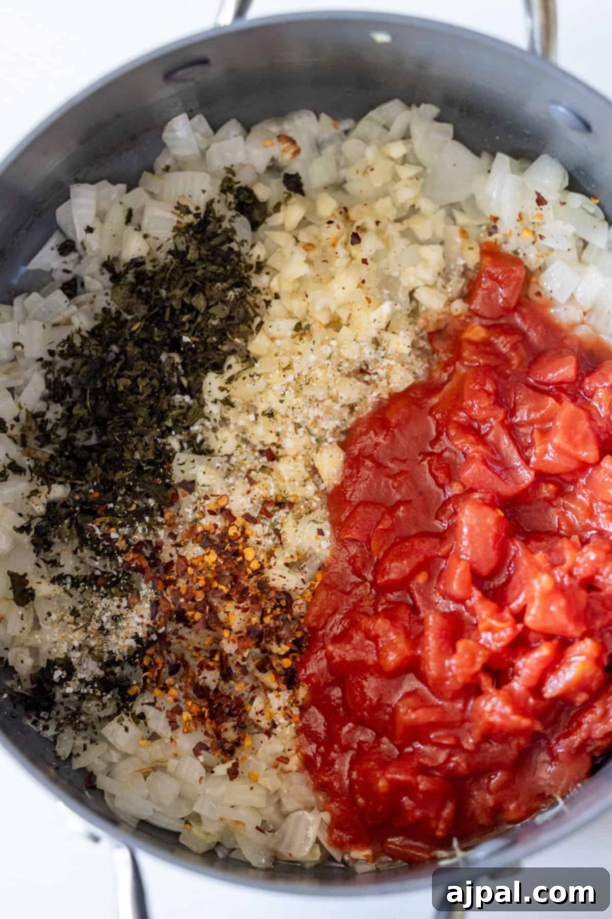 Marry Me Zucchini and Bean Delight 9 A saucepan containing sautéed diced onions, dried herbs, red pepper flakes, beans, and chopped tomatoes, arranged in separate sections before mixing—a vibrant base perfect for exploring zucchini recipes.