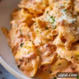 My Edible Soulmate: Tortellini 11 Close-up of creamy Marry Me Tortellini in a tomato-based sauce, garnished with chopped herbs and grated parmesan cheese.