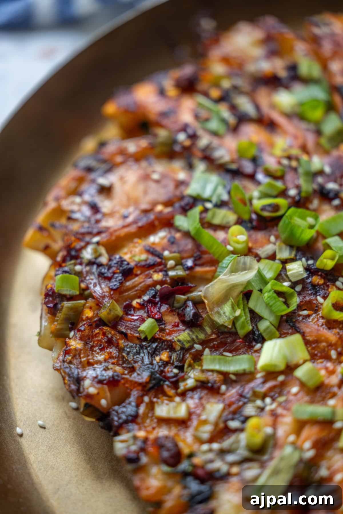 Spicy Potsticker Crunch Torte 4 A close-up of a savory Bok Choy Pancake, topped with chopped green onions, sesame seeds, and a browned, crispy surface.