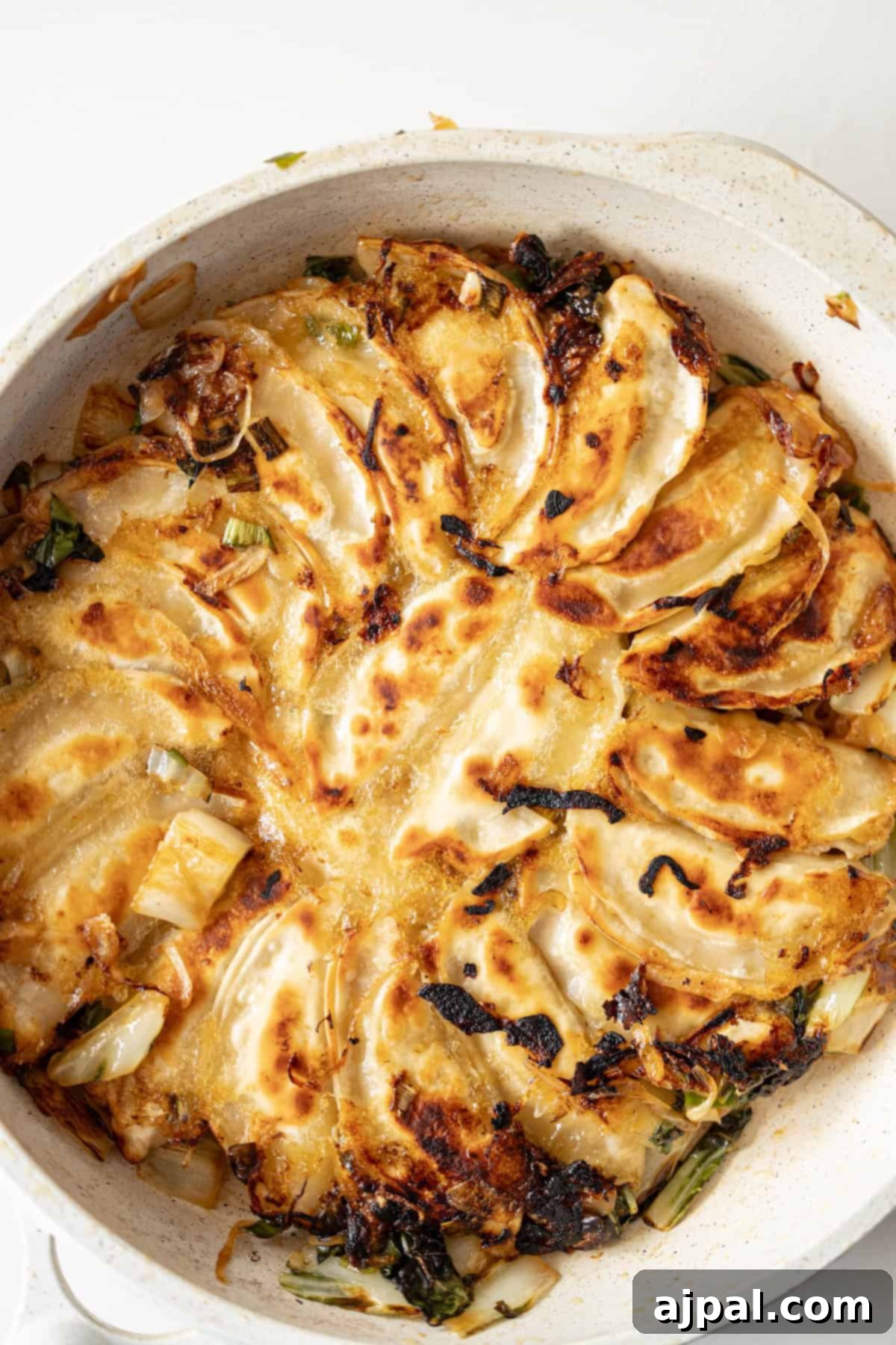 Spicy Potsticker Crunch Torte 9 A skillet filled with browned and crispy fried potstickers arranged in a circular pattern.