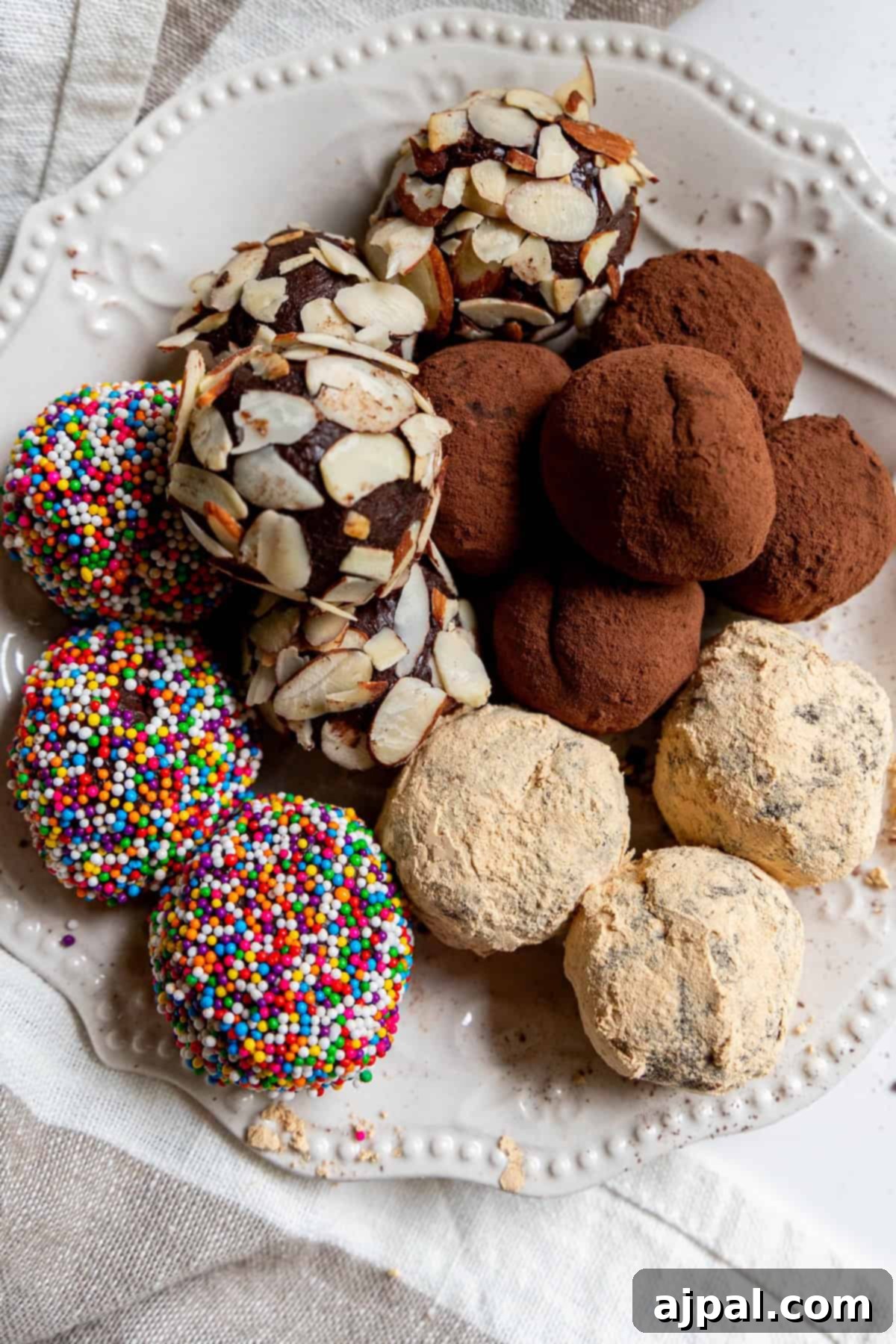 A plate of chocolate truffles awaits, some coated in sliced almonds, others dusted with cocoa powder or powdered sugar, and a few adorned with colorful sprinkles.