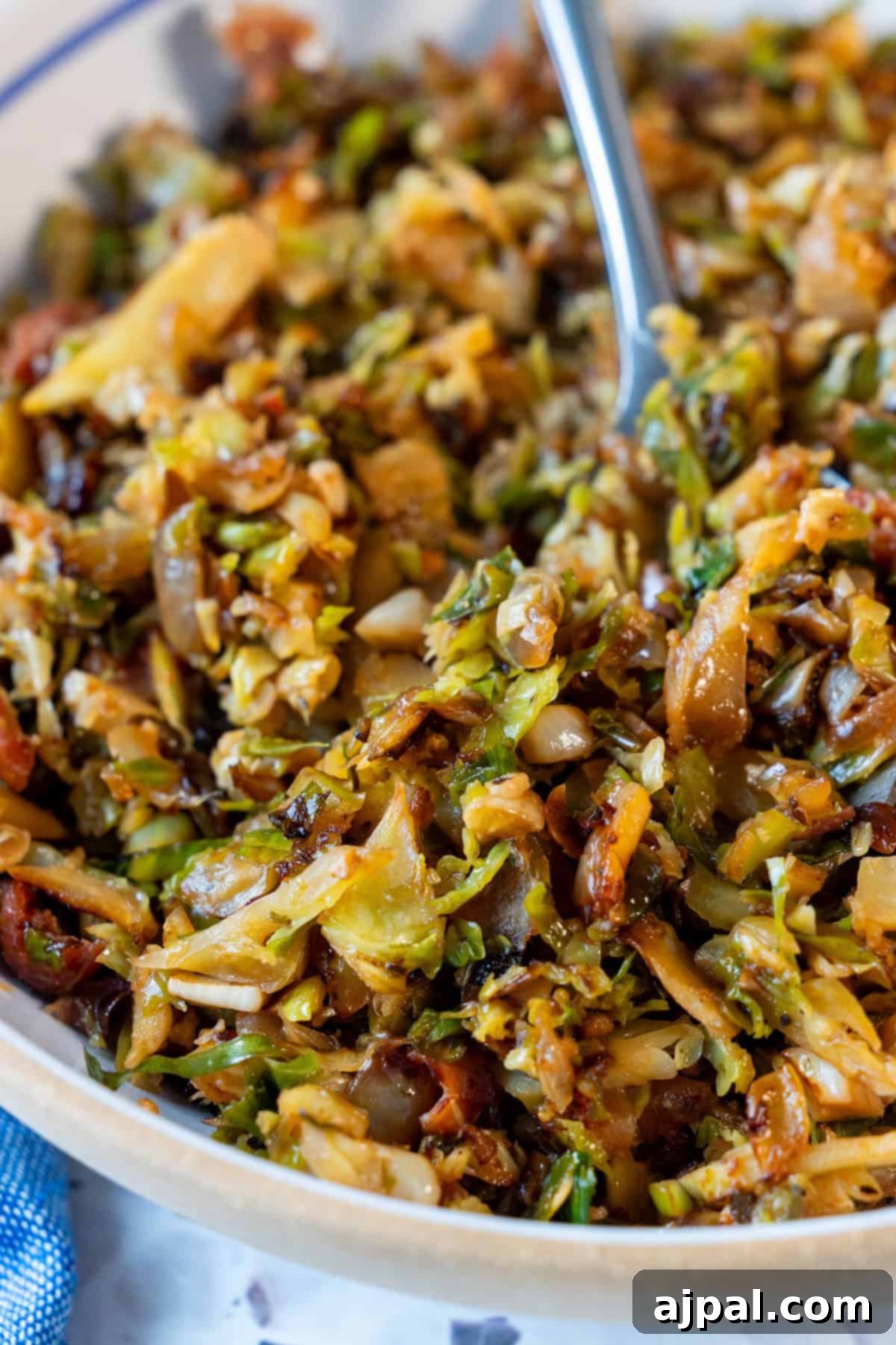 A close-up of sautéed and crispy shredded Brussels sprouts in a bowl with a serving spoon, showcasing the perfect texture of Brussels Sprouts Hash.