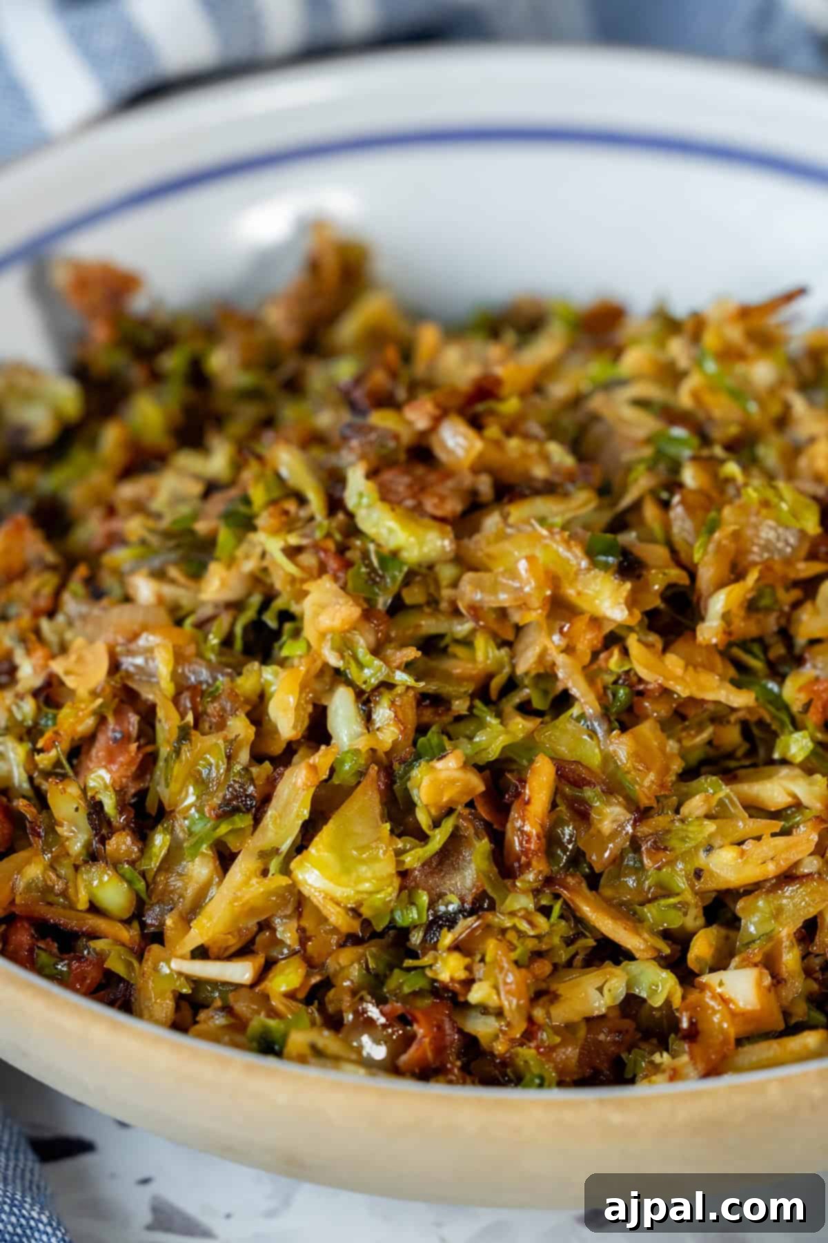 A close-up of beautifully caramelized shredded Brussels sprouts mixed with golden-brown pancetta in a shallow bowl, ready to serve.