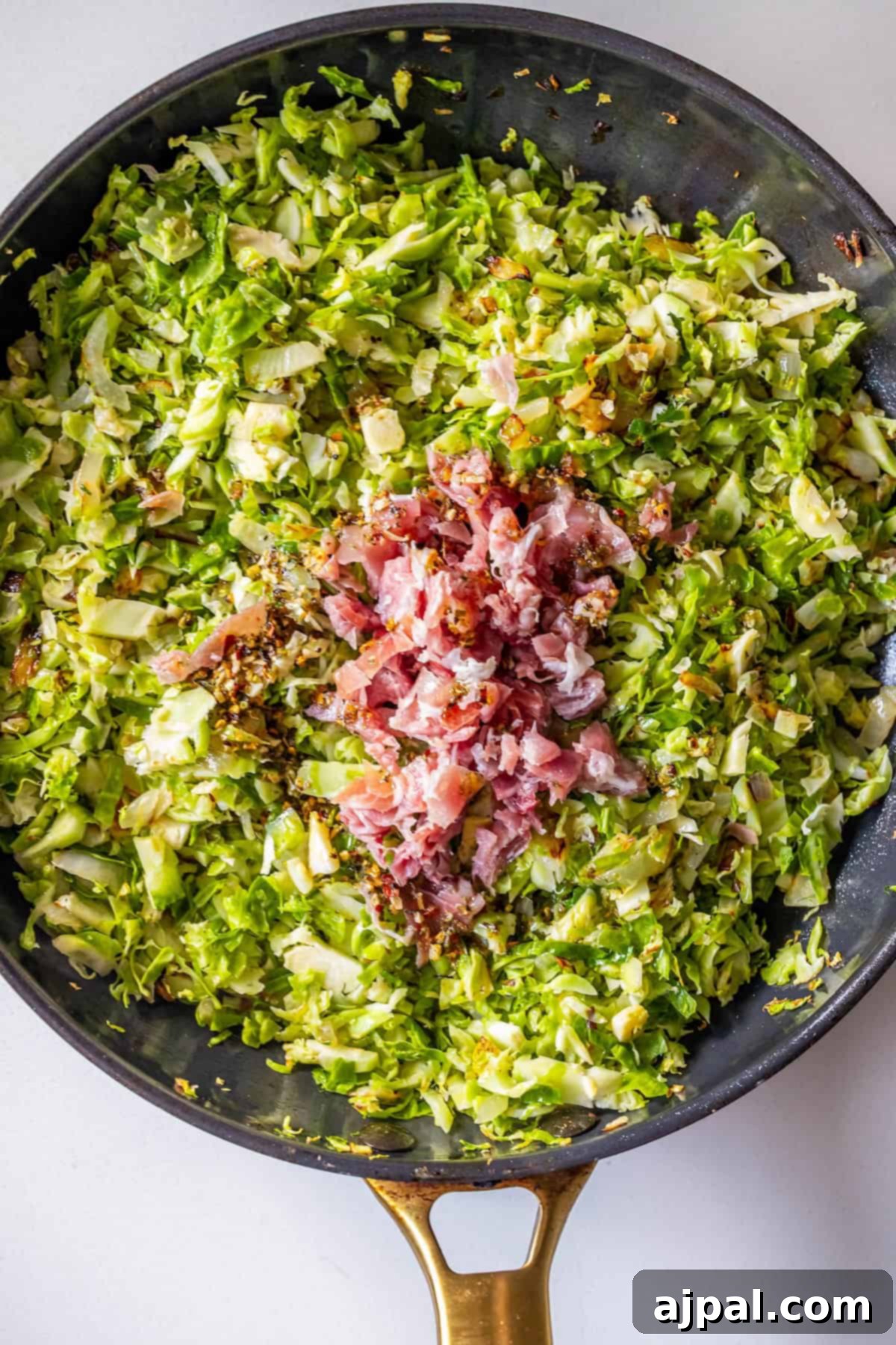 Brussels Sprouts Hash with diced pancetta sizzles in a black skillet with a gold handle, creating a savory, colorful skillet hash perfect for any meal.
