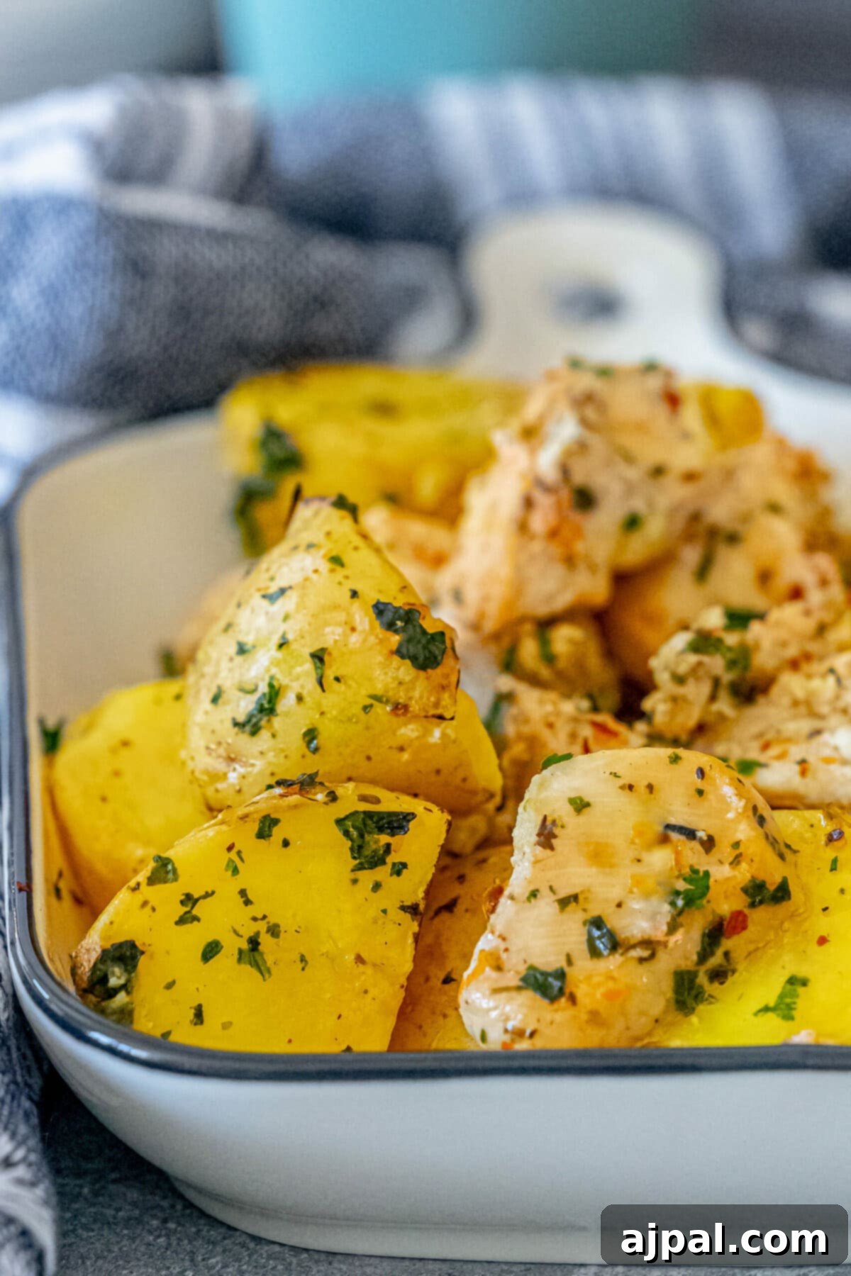 Simple Savory Chicken Bakes 13 Baked chicken and tender potatoes, seasoned with fresh herbs, in a rustic white baking dish. This one-pot meal showcases golden-brown chicken pieces alongside perfectly roasted potatoes, creating a simple yet flavorful dish.