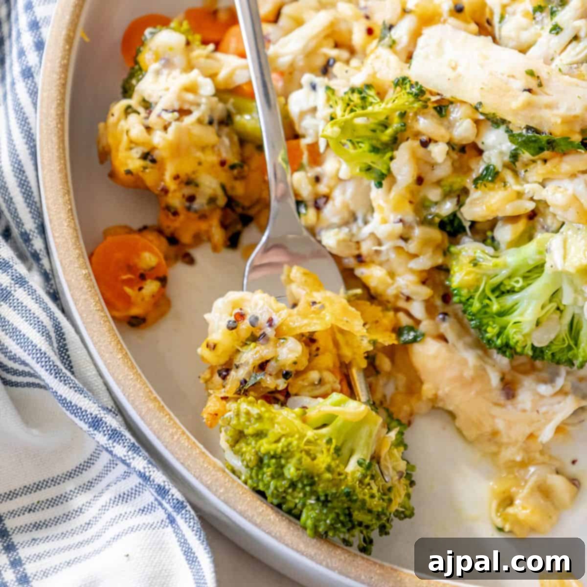 Simple Savory Chicken Bakes 7 A plate of cheesy chicken and broccoli with a fork, showing melted cheese over tender chicken and vibrant green broccoli florets, creating a comforting and delicious meal.