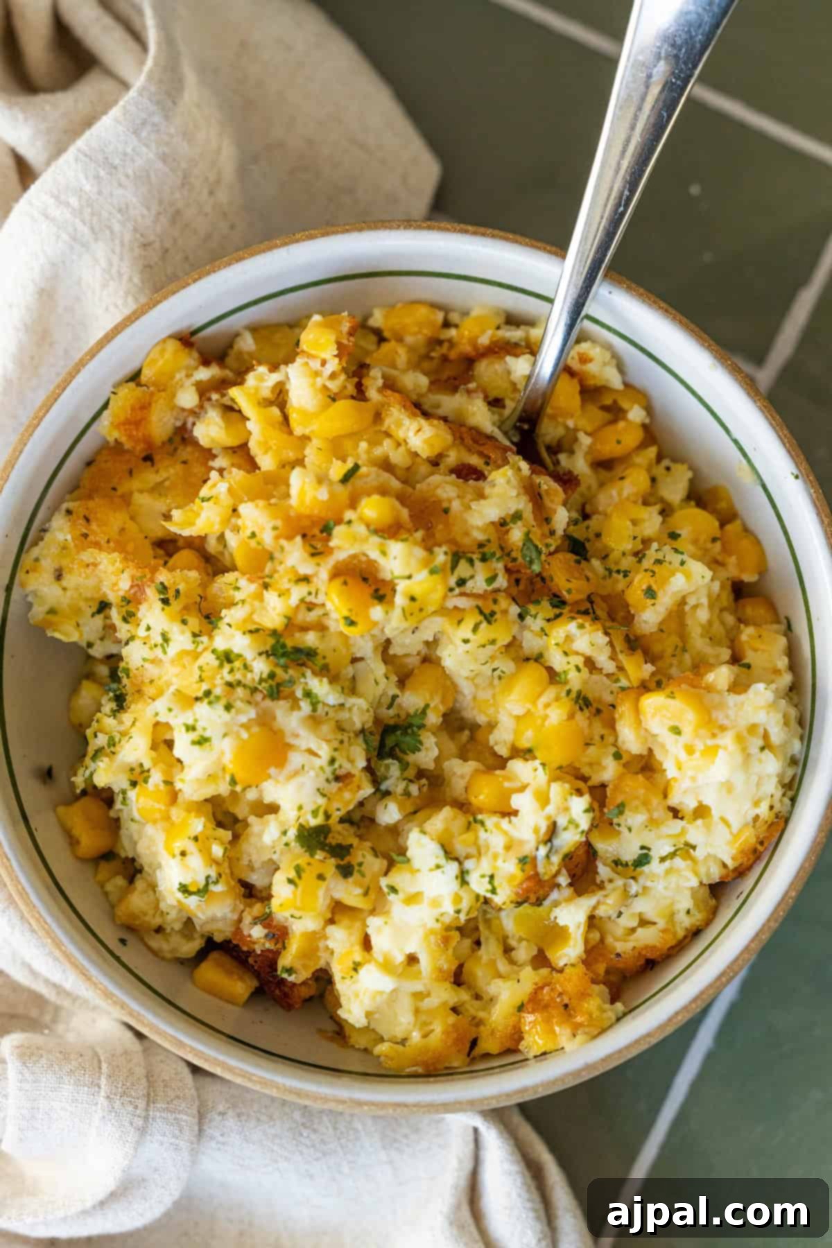 Close-up of a rich and creamy corn pudding casserole with fresh herbs, perfect for a cozy family dinner or festive occasion.