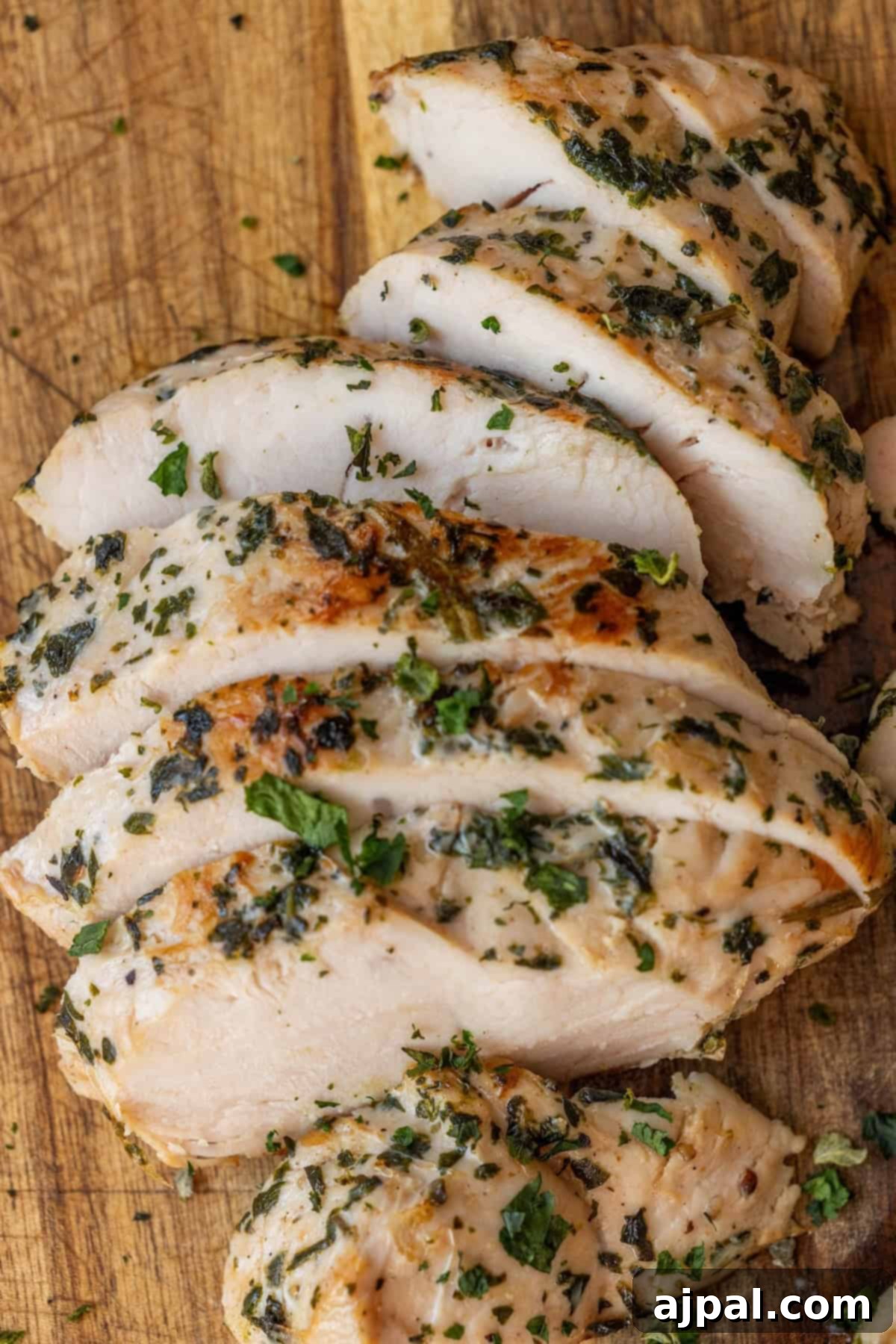 Sliced herb-seasoned cooked chicken breast, perfect inspiration for an easy turkey recipe.