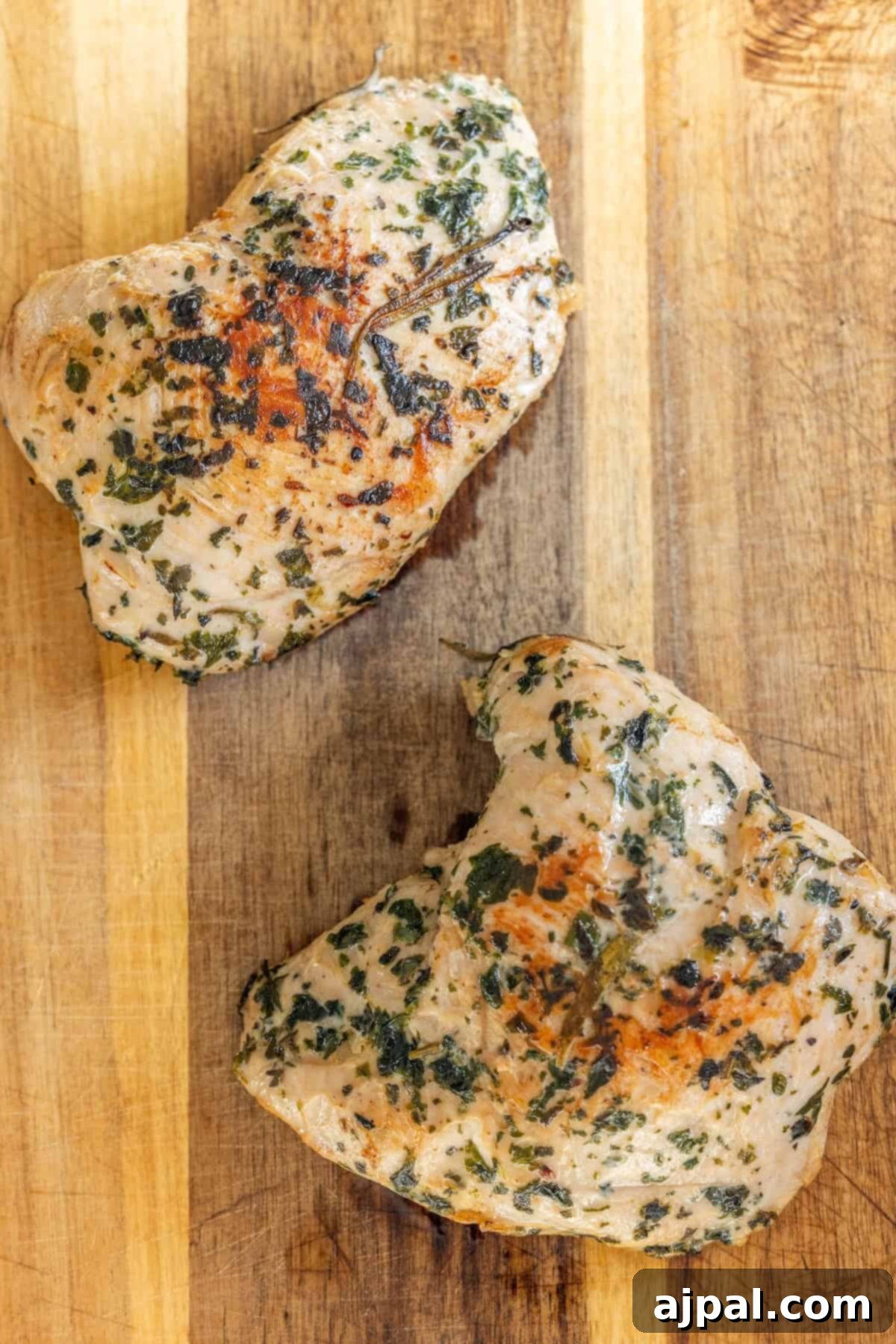 Two cooked, herb-seasoned turkey tenderloins on a cutting board.