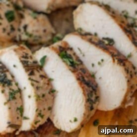 Sliced cooked chicken breast garnished with chopped herbs.