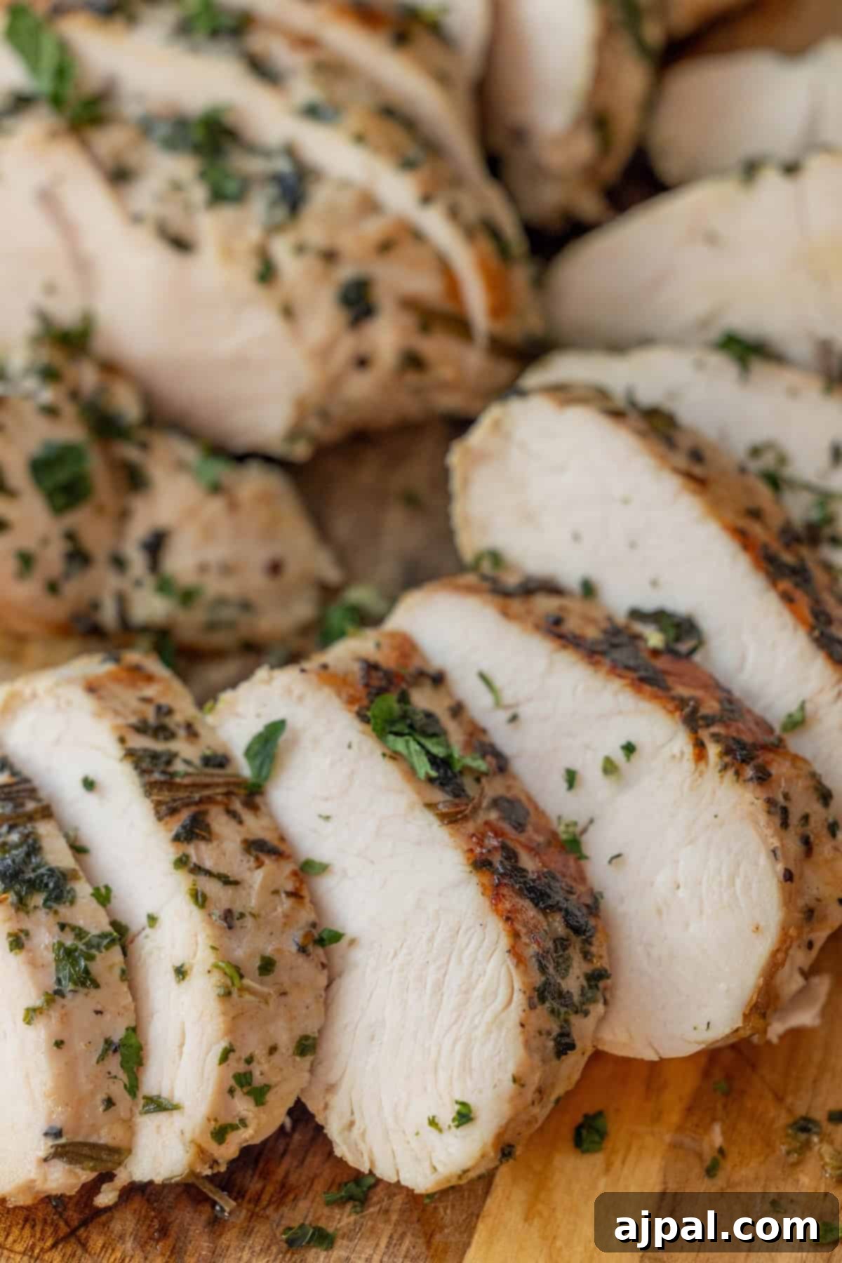 Sliced, cooked chicken breast with herbs, ideal for an easy turkey recipe like baked turkey tenderloin.