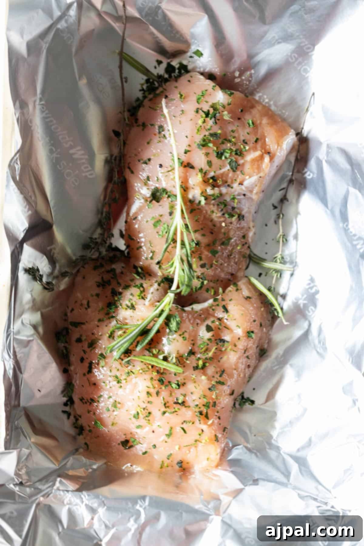 Raw turkey tenderloins seasoned with herbs.