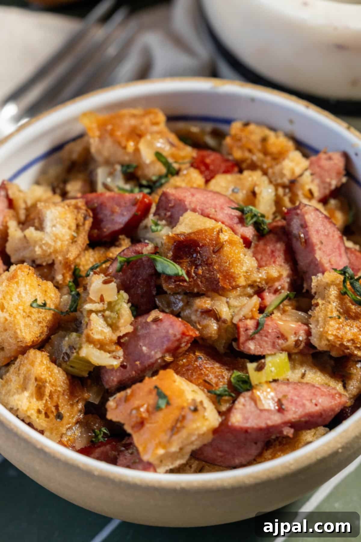 A tempting bowl of Polish Kielbasa Stuffing featuring bread cubes, savory sausage slices, fresh vegetables, and fragrant herbs.