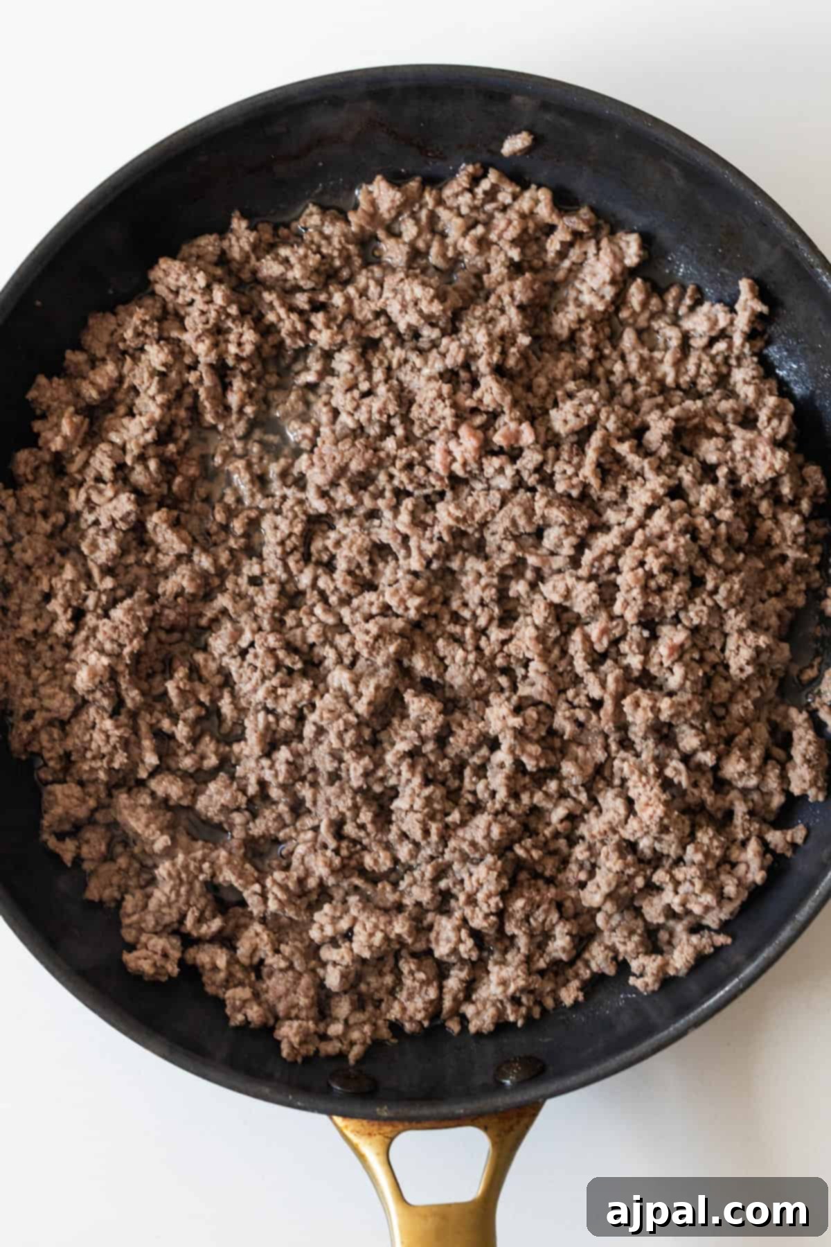 Fiery One-Pot Taco Skillet 5 Cooked ground beef in a black skillet with a gold handle, shown from above on a white background—perfect for an easy taco and rice skillet dinner.