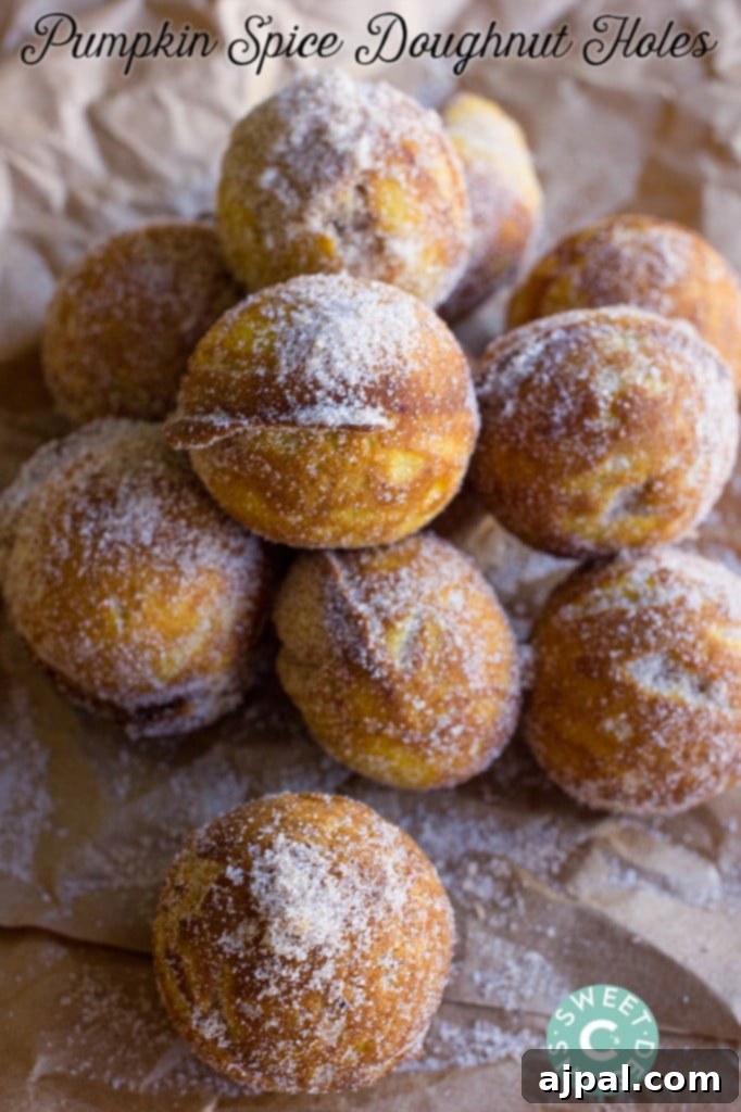 Stack of golden baked pumpkin spice donut holes, generously coated in cinnamon and caster sugar.