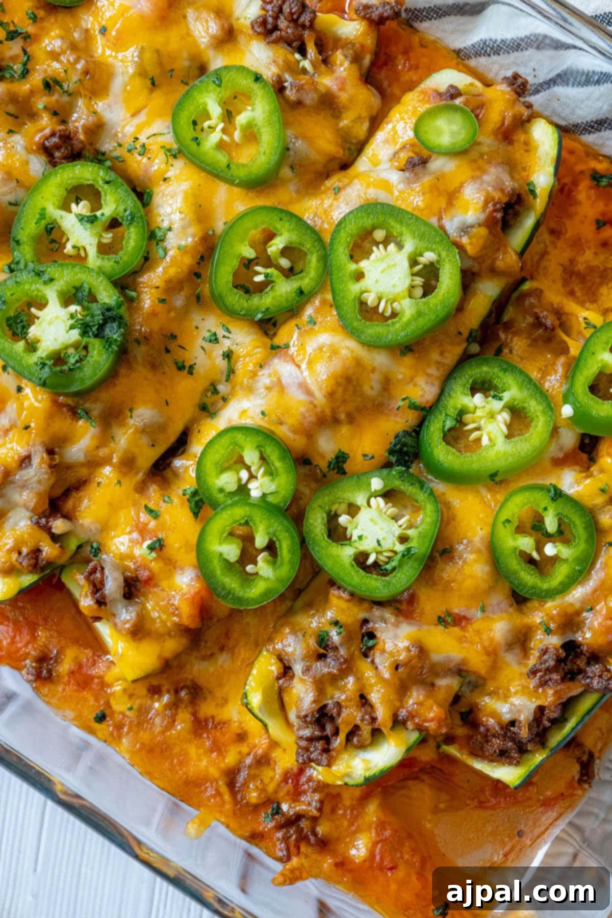 Loaded Zucchini Boats 11 Close-up of baked taco stuffed zucchini, golden cheese bubbling over a rich filling, garnished with fresh jalapeños.