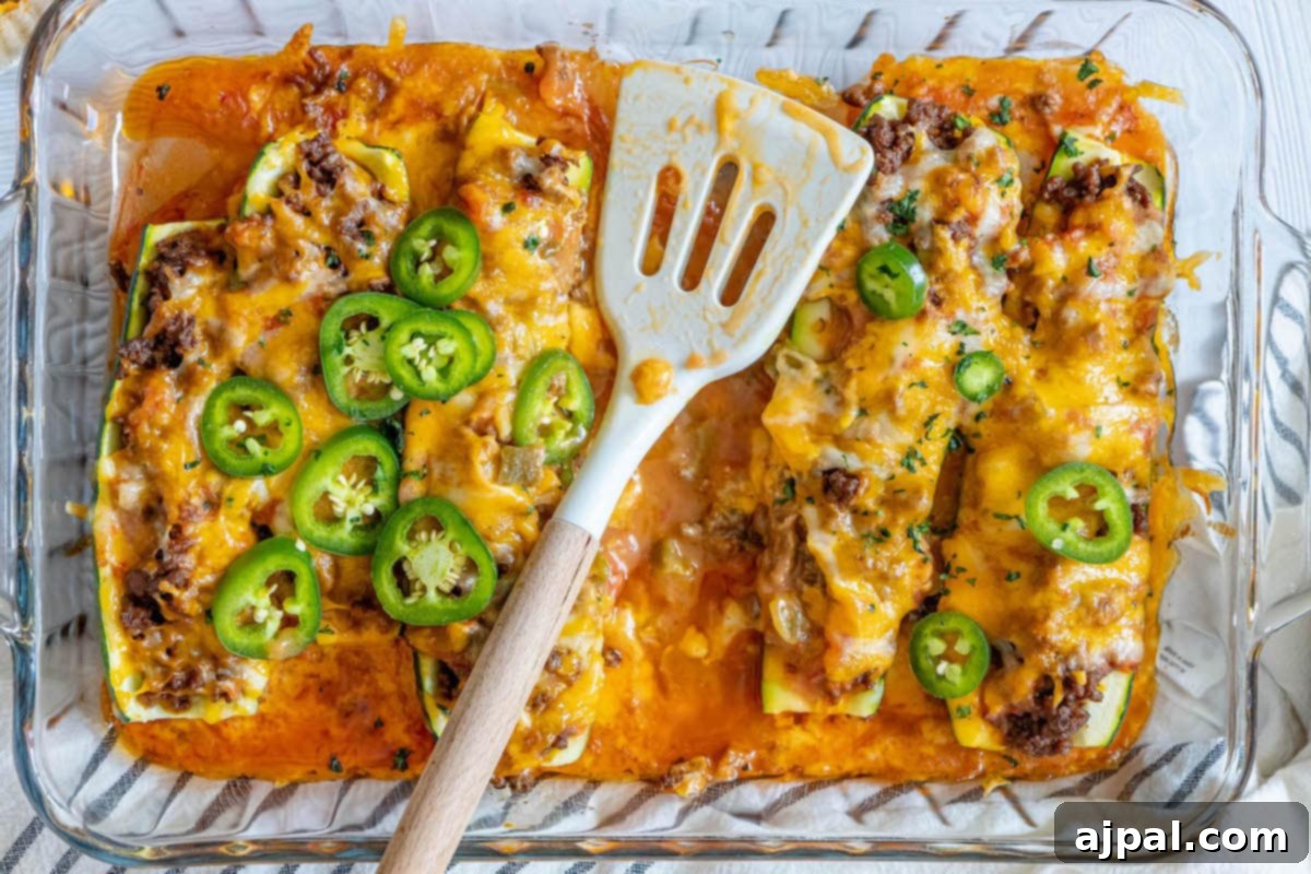 Loaded Zucchini Boats 13 Cheesy zucchini enchiladas baked in a dish with a spatula, showcasing a perfect golden crust and tender filling.