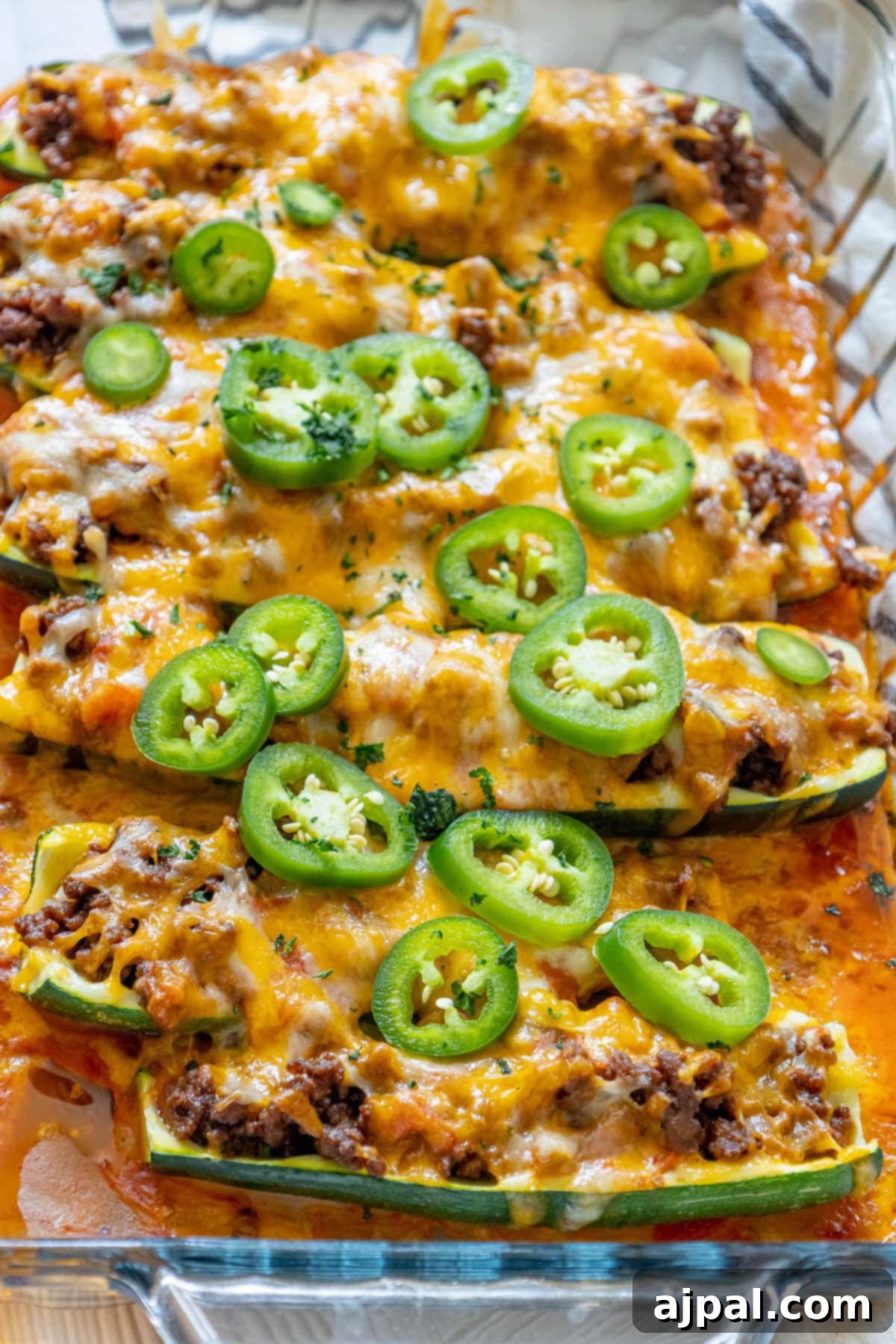 Baked Zucchini Treasures 3 Taco stuffed zucchinis baked in a glass dish with enchilada sauce and sliced jalapeños on top
