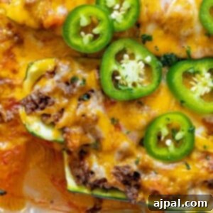 Delicious taco stuffed zucchini boats, golden brown with melted cheese and fresh jalapeños, captured in a recipe picture.