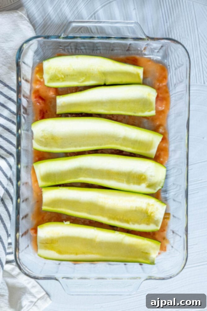 Baked Zucchini Treasures 8 Cored and halved zucchinis in a glass baking dish with green enchilada sauce in the bottom