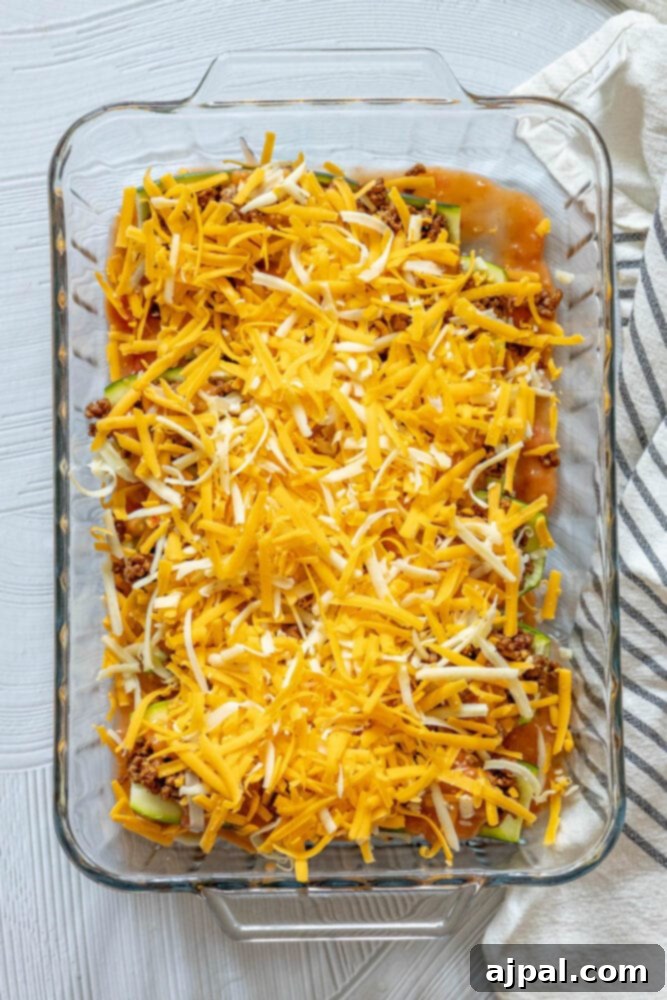 Loaded Zucchini Boats 10 Zucchini boats in a glass baking dish, beautifully topped with melted cheese over the taco filling and enchilada sauce, ready for the oven.