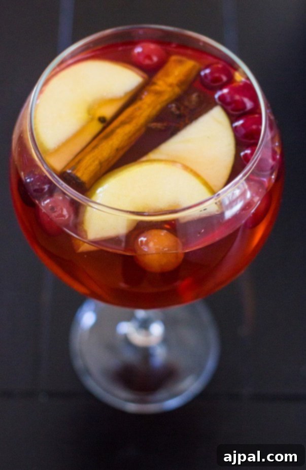 A festive glass of cranberry sangria with apples and cinnamon, perfect for Christmas celebrations.