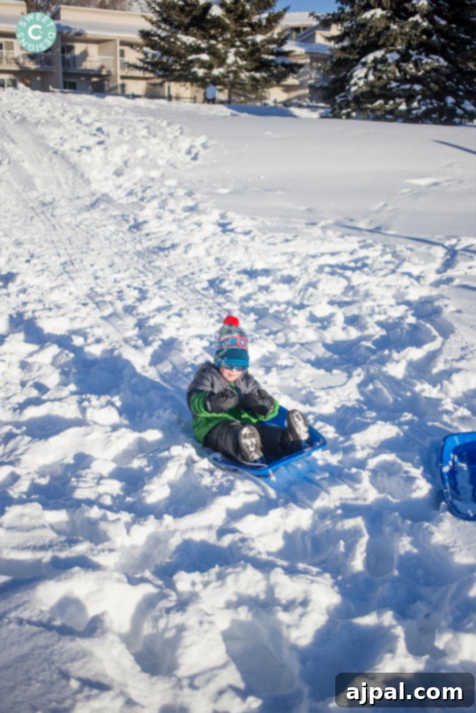Avon Colorado Alpine Escape 8 A child joyfully sledding down a snow-covered hill in Avon, Colorado, surrounded by winter beauty.