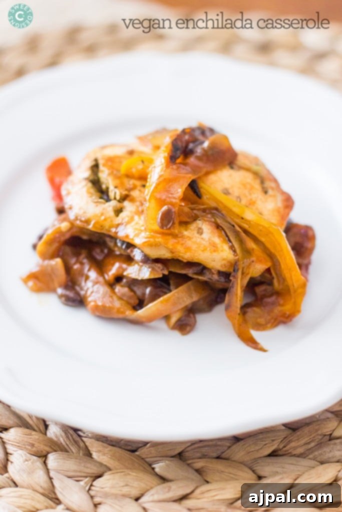 Hearty Paleo Vegan Enchilada Bake 2 A vibrant Paleo Vegan Enchilada Casserole, showcasing layers of bell peppers, mushrooms, and seeds, artfully arranged like lasagna on a white plate. This colorful dish is a perfect example of a healthy and satisfying meat-free meal.