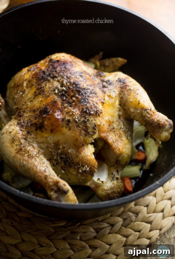 Perfect Thyme Roast Chicken 5 A whole roast chicken with fresh thyme sprigs, cooking in a cast iron skillet.