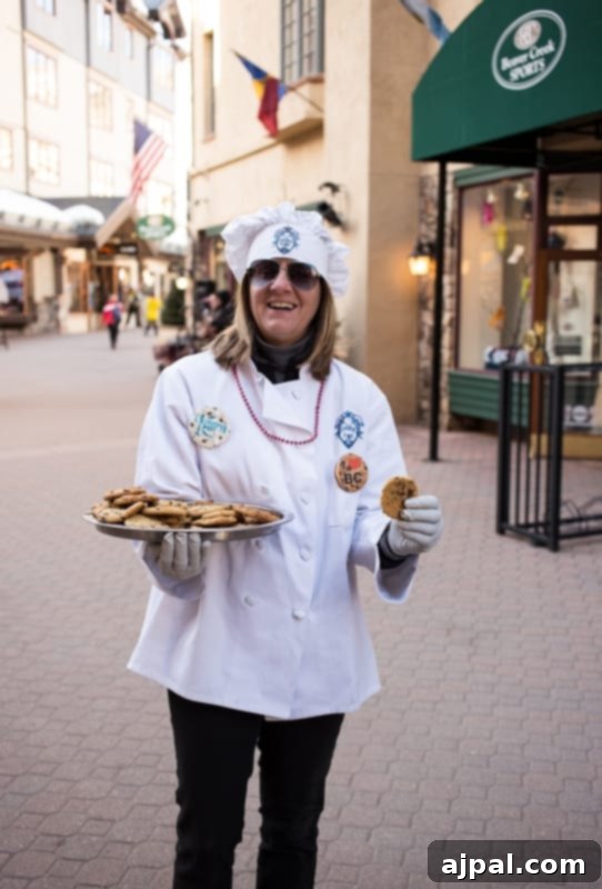 A chef in a traditional hat offers a plate of renowned chocolate chip cookies, a beloved tradition at Beaver Creek Ski School.