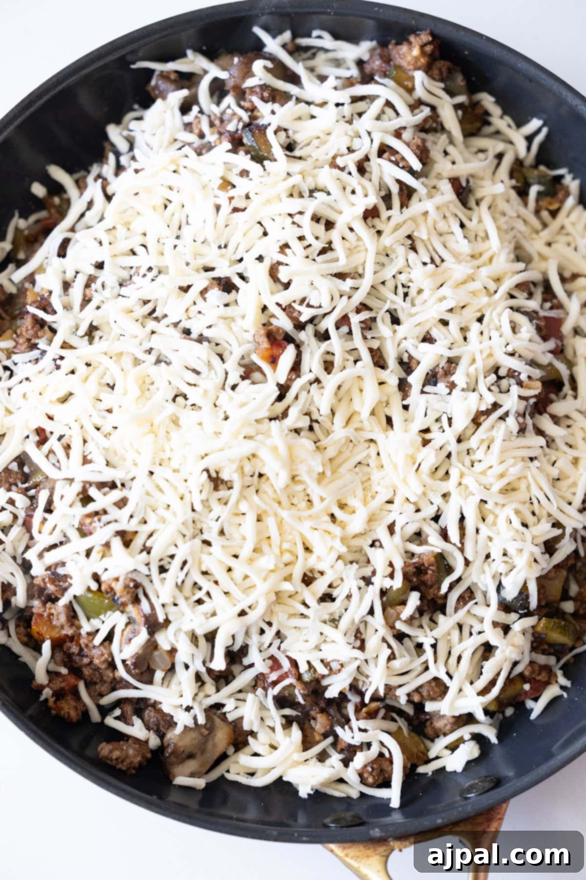 Loaded Cheesy Taco Skillet 9 A Cheesy Taco Skillet filled with cooked ground meat, vegetables, and topped with a generous layer of shredded cheese.