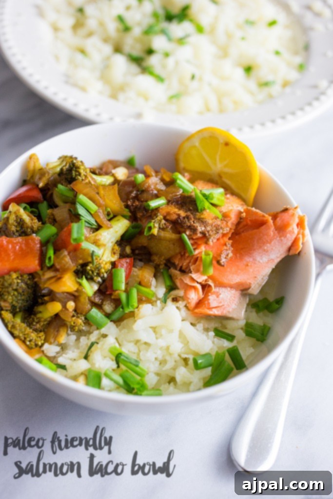 Paleo Salmon Taco Power Bowls 2 A beautifully arranged bowl featuring fluffy cauliflower rice, perfectly cooked salmon, crisp broccoli florets, fresh chives, and a bright lemon wedge, ready to be enjoyed as a healthy and flavorful meal.