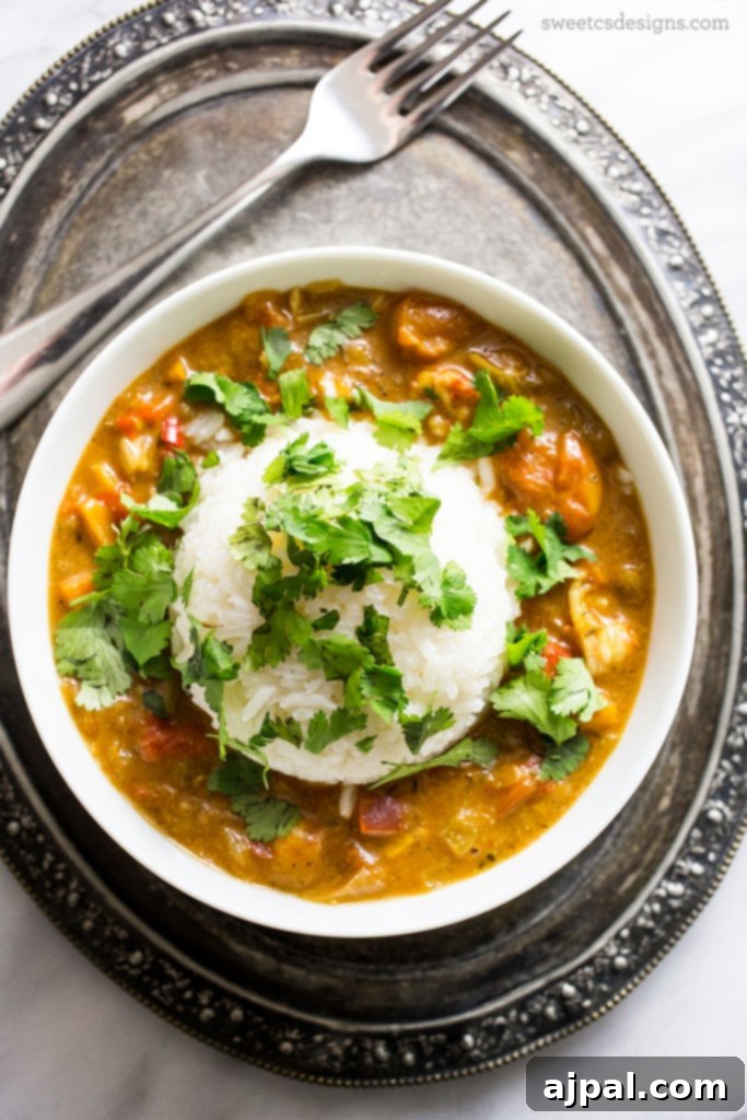 A vibrant bowl of Cajun Langoustine Étouffée, featuring tender langoustines in a rich, spicy sauce, garnished with fresh cilantro and served alongside fluffy white rice.