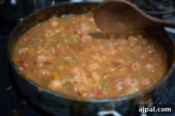 Smothered Langoustine 9 A wooden spoon rests in a pot of simmering Langoustine Étouffée, showcasing its rich texture and enticing color.