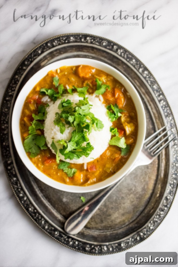 A perfectly portioned bowl of Langoustine Étouffée with white rice and a fork, highlighting the vibrant colors and appealing presentation of the dish.