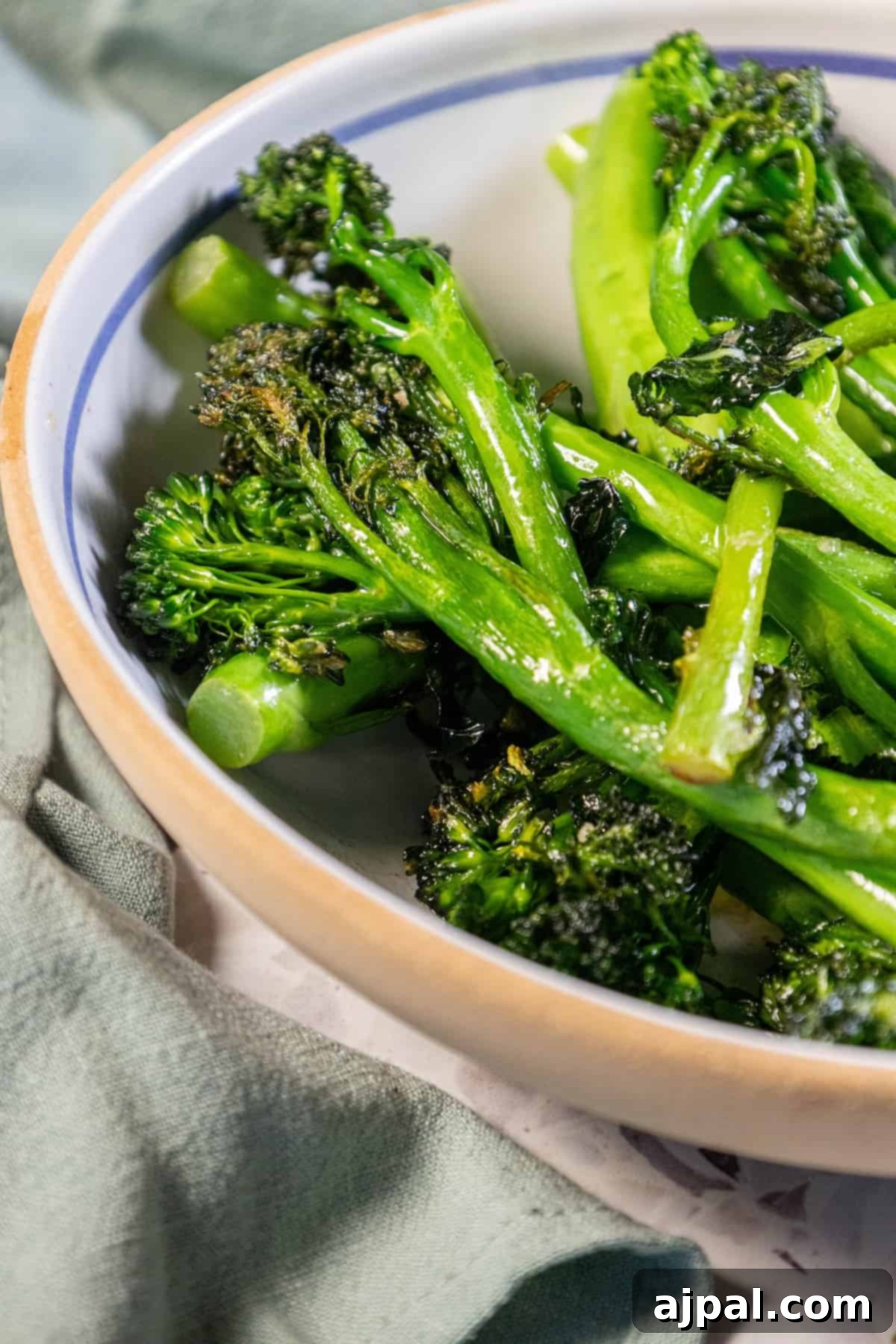 Pan-fried broccolini in a bowl on a table, perfectly browned and tender.