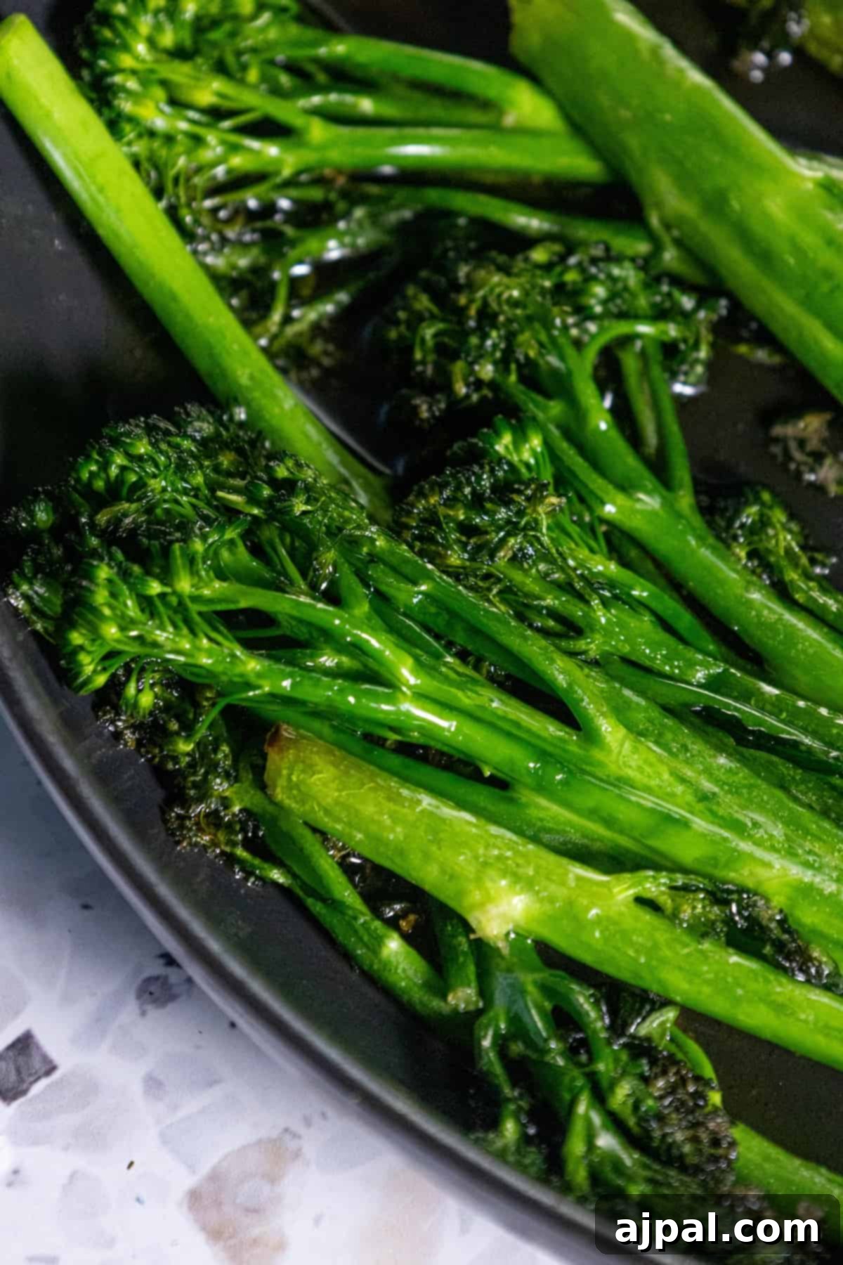 A plate of perfectly sautéed broccolini on a rustic wooden table.