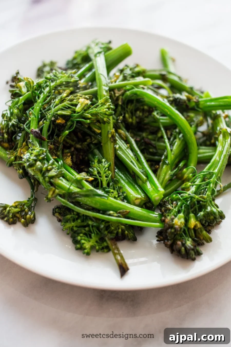 Close-up picture of perfectly pan-fried broccolini on a white plate, ready to serve.