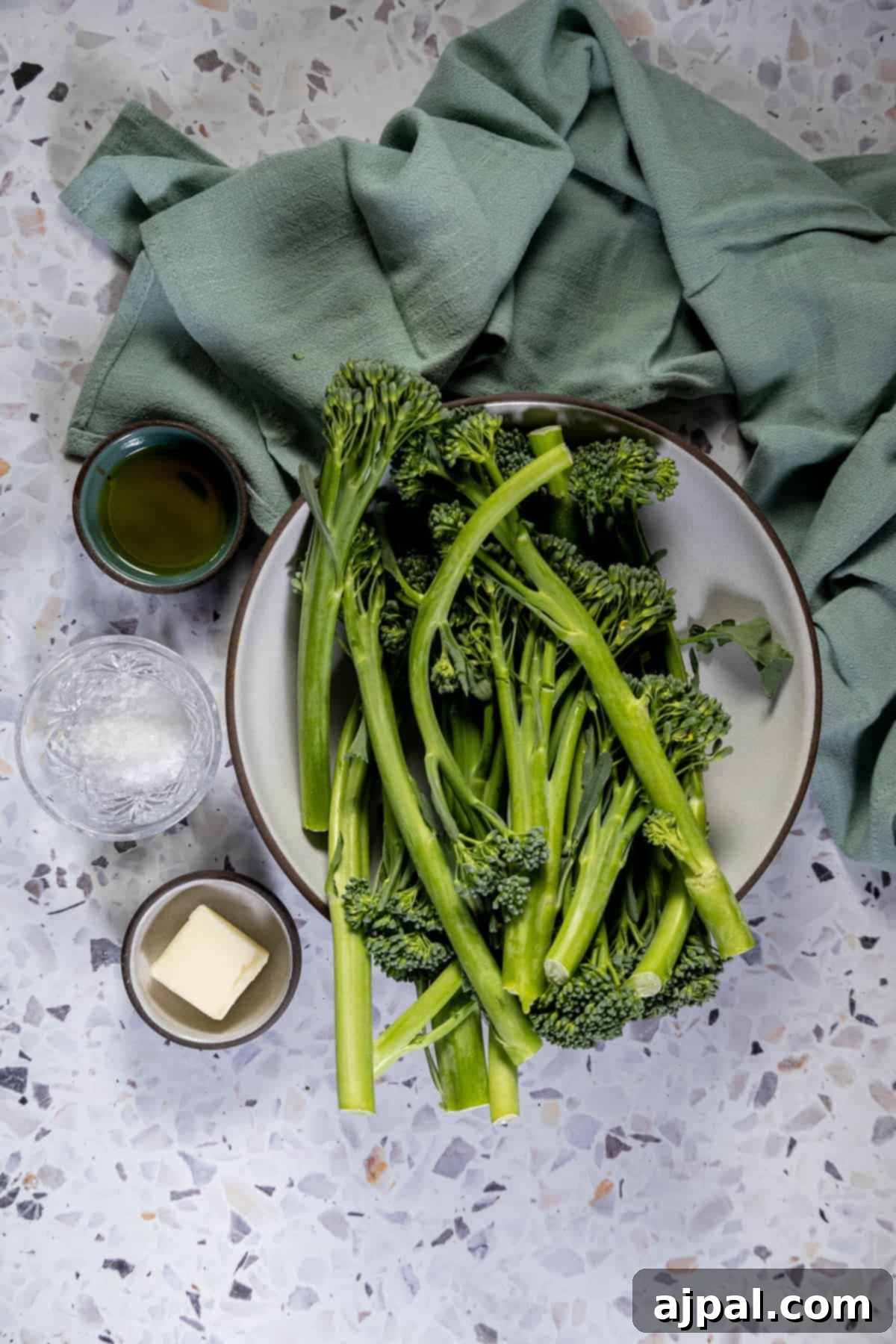 A bowl of fresh broccolini and butter on a table, prepped for a delicious keto baby broccoli recipe.