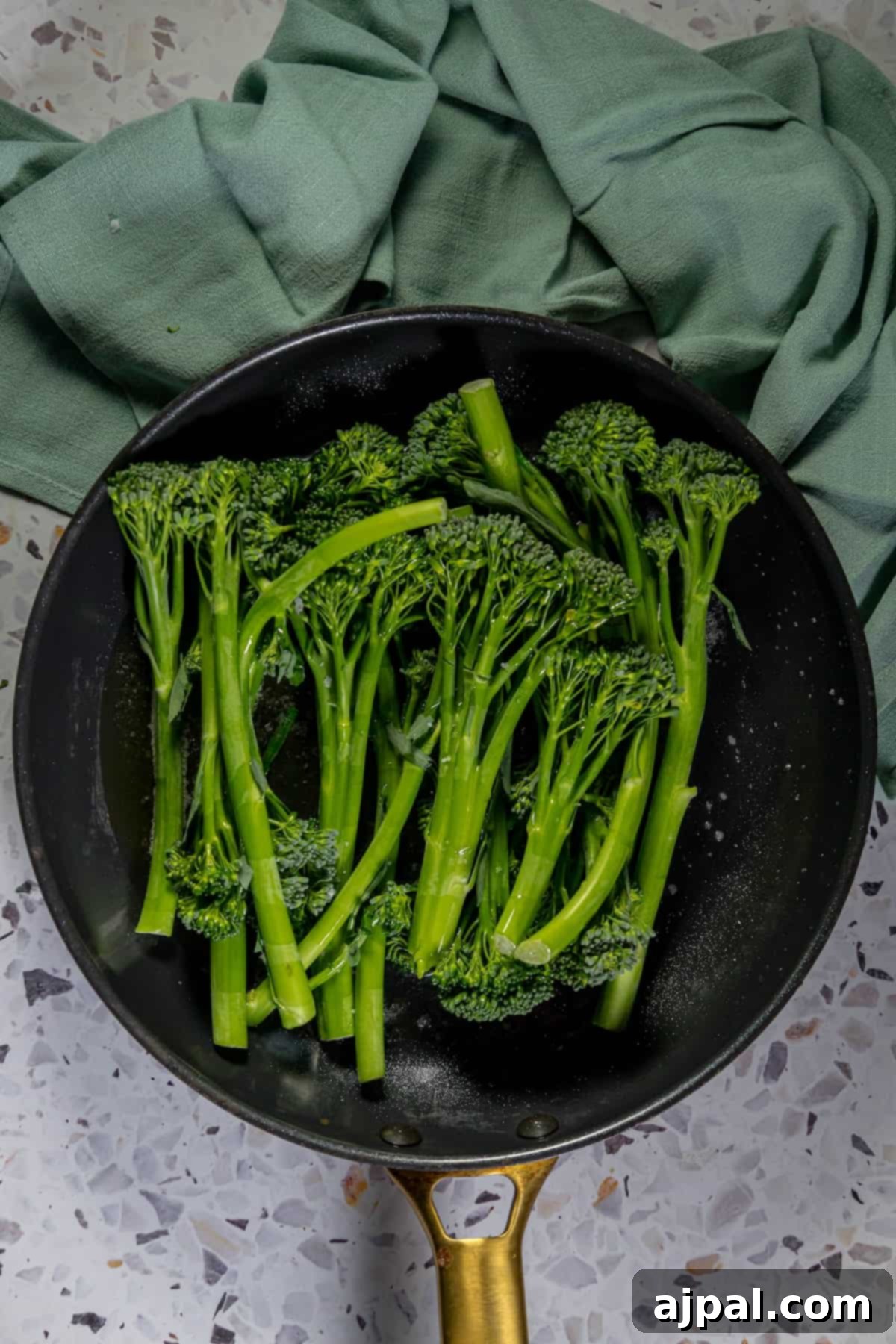 A sauteed broccolini dish cooking in a frying pan, showing the browning process.