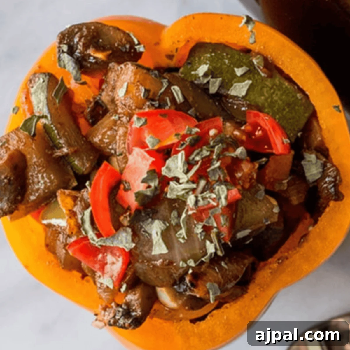 Fiery Plant-Based Stuffed Peppers 4 Spicy vegan stuffed bell pepper with diced tomatoes, mushrooms, and herbs on top, served on a white plate.