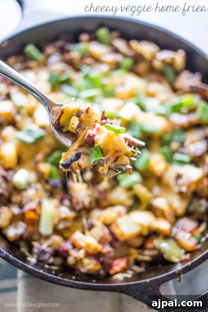 Cast iron skillet filled with cheesy veggie home fries, garnished with fresh green onions.