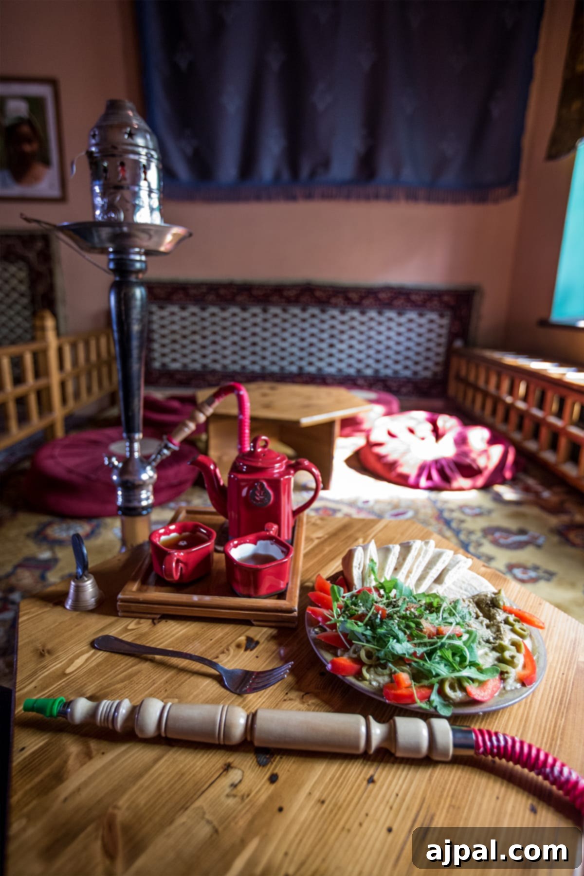 A wooden table adorned with a plate of delicious food and a traditional hookah, offering a moment of relaxation in Krakow's Jewish District.