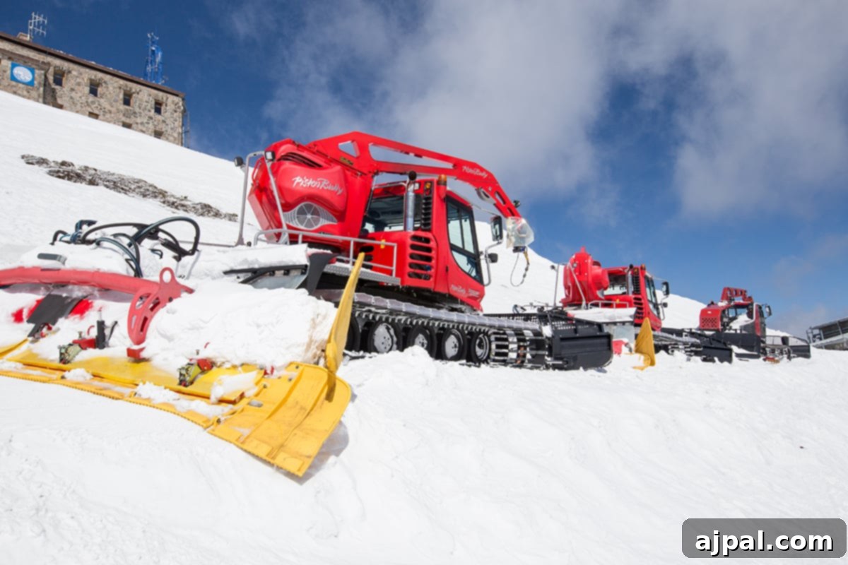 Zakopane Poland Mountain Resort 5 Red snow plows parked on a snow-covered hill against a backdrop of snowy mountains in Zakopane, Poland.