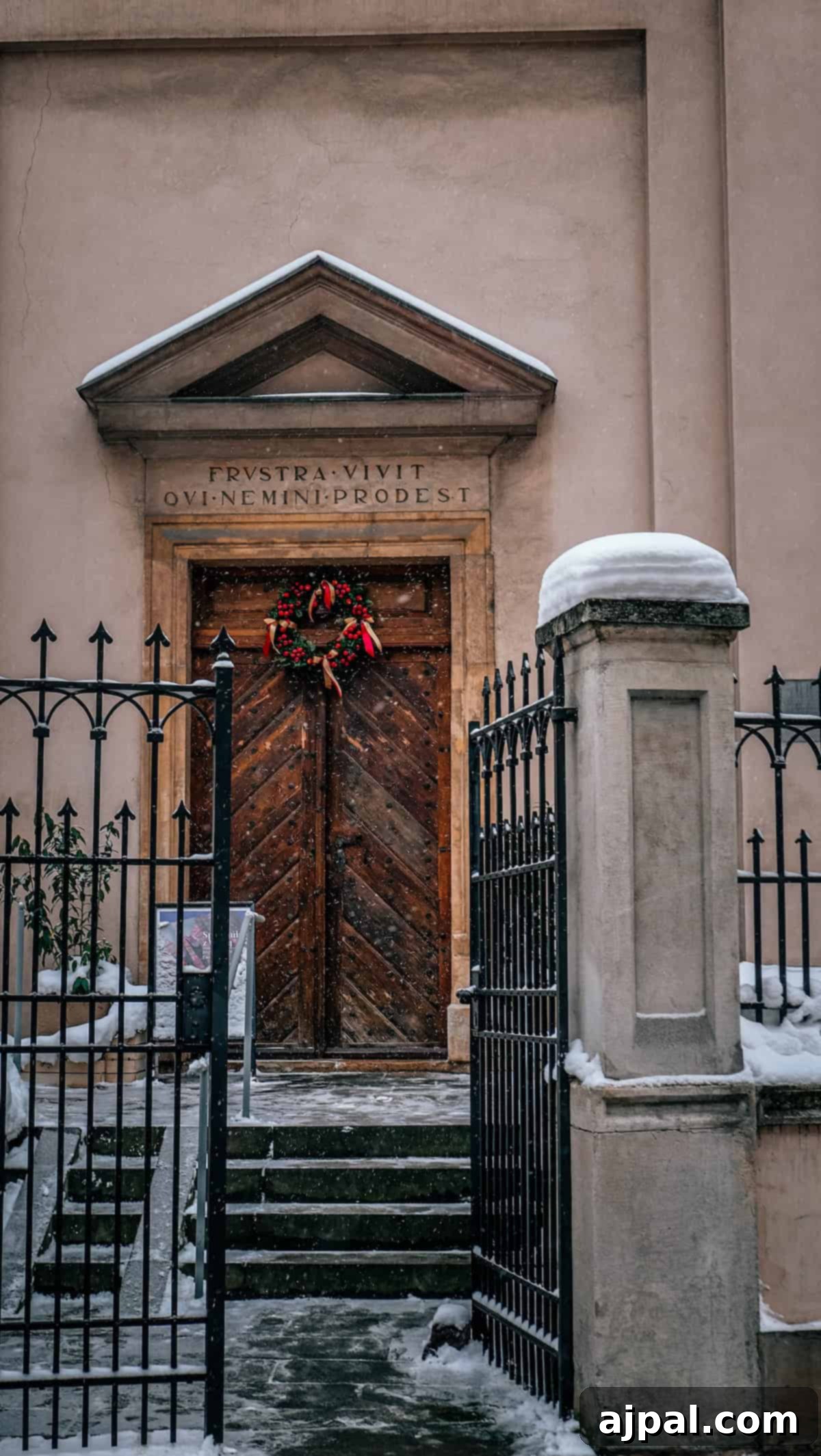 Krakow: Poland's Royal City 5 A charming snow-covered building entrance in Krakow, with an ornate wooden door and Latin inscription.
