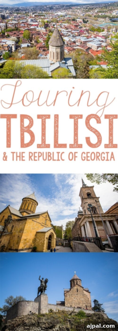 Tbilisi, the Republic of Georgia's captivating capital city, showcasing ancient stone churches and distinctive red-tiled roofs, nestled in a lush valley with mountains in the background.